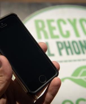 cell phone in front of recycling sign